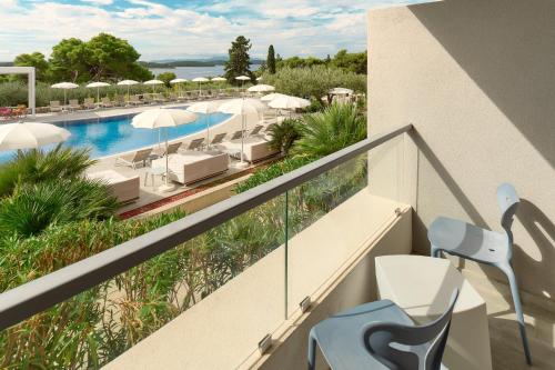 a balcony with a pool and chairs and umbrellas at Pharos Hvar Bayhill Hotel in Hvar