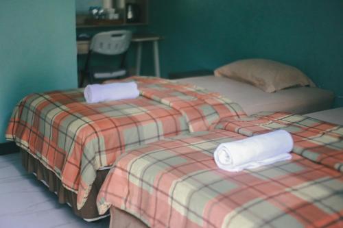 two beds with towels on them in a room at Jatimas Hijau Hotel & Villa in Kopo 2
