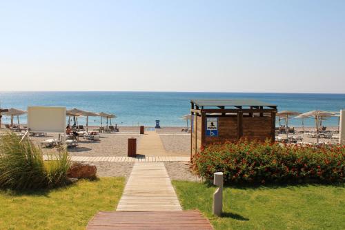 a wooden pathway leading to a beach with umbrellas at Elysium Resort & Spa in Faliraki
