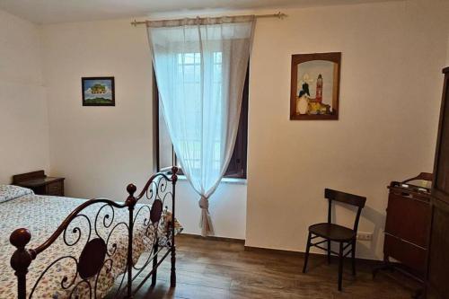 a bedroom with a bed and a chair and a window at La Casa Rossa affittacamere in Cairo Montenotte