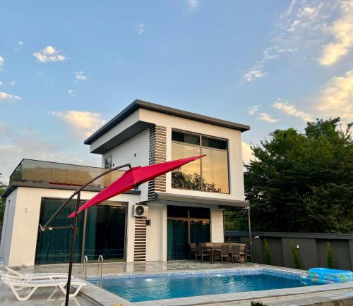 a house with a swimming pool and a red umbrella at AZ Villa in Gabala in Gabala