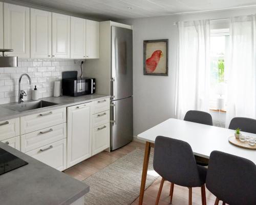 a kitchen with white cabinets and a table with chairs at Backes Lillstuga in Borlänge