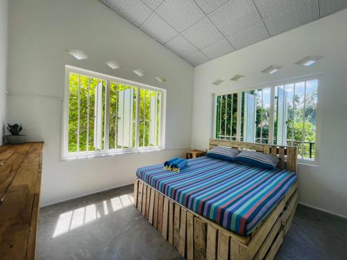 a bedroom with a bed in a room with windows at Berg house Hostel in Mirissa