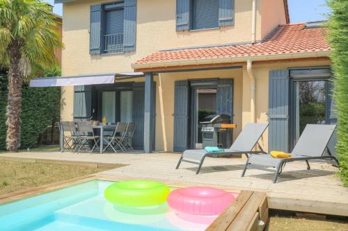a swimming pool with two lawn chairs and a house at Sunny House - Villa 4 chambres - Saint Genis Les Ollières in Saint-Genis-les-Ollières