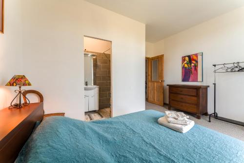a bedroom with a blue bed and a bathroom at Villa Costebelle in Tulette
