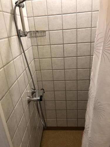 a shower in a bathroom with white tiles at Kolding Midtby in Kolding