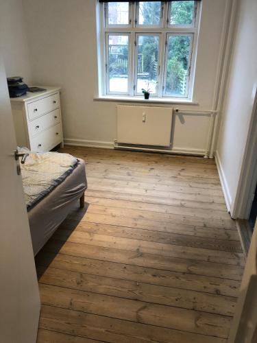 a bedroom with a bed and a window and a wooden floor at Kolding Midtby in Kolding