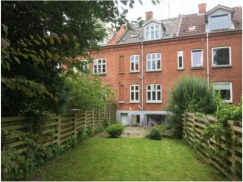 a large brick building with a fence and a yard at Kolding Midtby in Kolding
