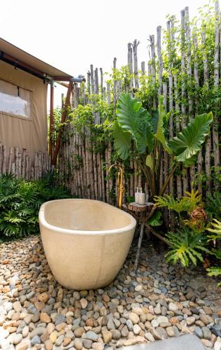 a bath tub in a garden with a fence at WoCAL Resort Ke Ga in Xóm Chum Găng