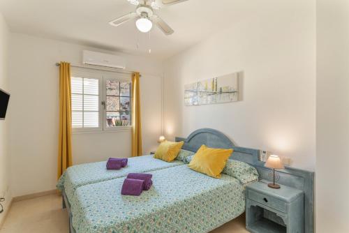 Un dormitorio con una cama azul con almohadas amarillas en Los Mangueros Beach 37 - Mogán, en Puerto de Mogán