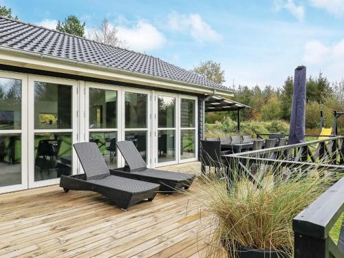 a deck with chairs and tables on a house at 5 star holiday home in Jerup in Jerup