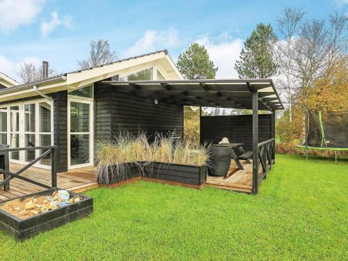a backyard with a wooden deck with a pergola at 5 star holiday home in Jerup in Jerup