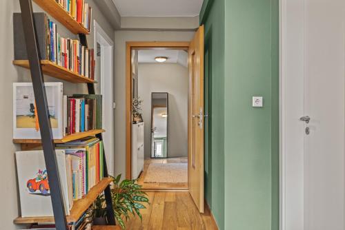 a hallway with green walls and wooden shelves filled with books at Cosy Haven Apartment in Reykjavík