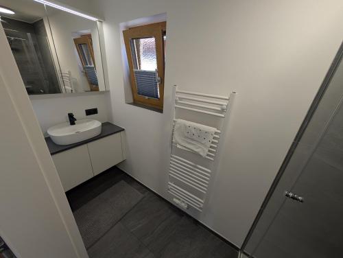 a white bathroom with a sink and a mirror at Ferienwohnung am Bauernhof, Seeblick, Bergpanorama in Keuschen