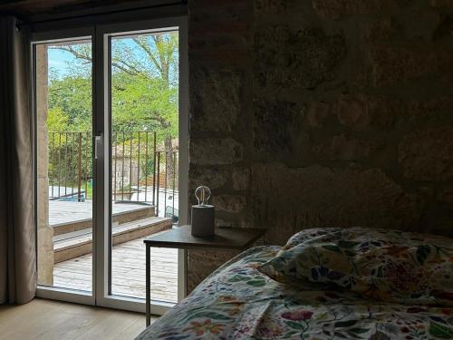 a bedroom with a bed and a sliding glass door at Gîte au cœur des Bastides Albigeoises in Le Verdier