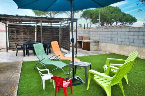 a group of chairs and a table with an umbrella at Family house with beautiful garden in Saint-Hippolyte
