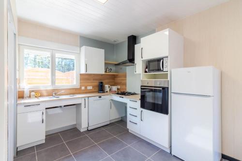a kitchen with white cabinets and a white refrigerator at Gite 1 de l'Orée du Bois in Thenon