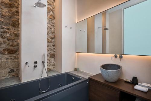 a bathroom with a tub and a sink and a mirror at Ambassadors Residence Boutique Hotel in Chania Town