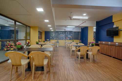 a dining room with tables and chairs and a tv at HOTEL SHITAL INN in Ahmedabad