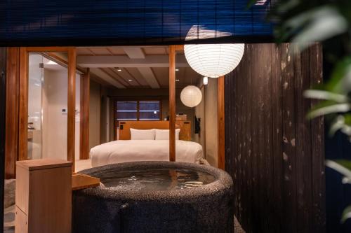 a bedroom with a bed and a tub in a room at Nazuna Kyoto Nishi Honganji in Kyoto