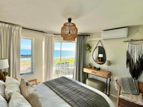a bedroom with a bed and a desk with a view of the ocean at Abode Africa in Bloubergstrand