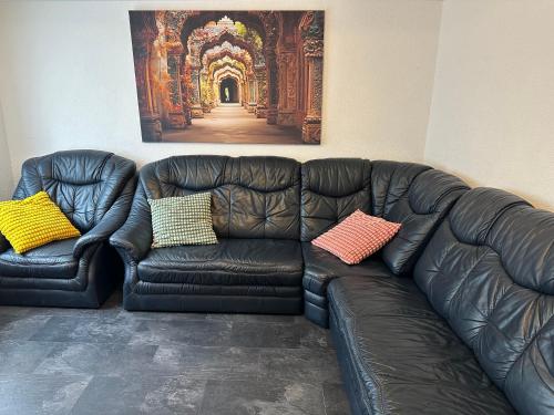 a black leather couch with two colorful pillows on it at Rhaunen Gasthaus in Rhaunen