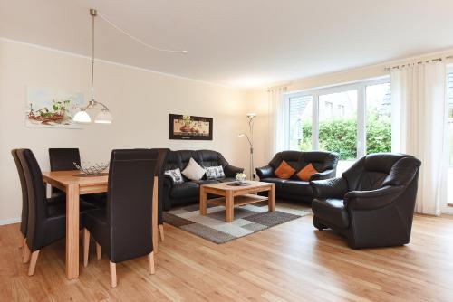 a living room with black leather furniture and a table at Ferienhaus Wormser Tor - Uns Huus an t Küst in Bensersiel