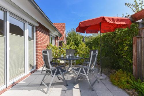 a table and chairs with an umbrella on a patio at Ferienhaus Wormser Tor - Uns Huus an t Küst in Bensersiel