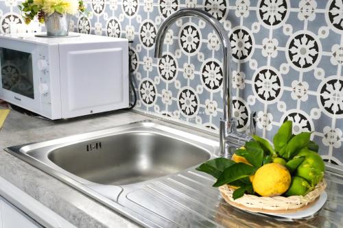 a kitchen sink with a bowl of fruit and a microwave at Annina'S Home Panoramic sea view By Sicily Home Solutions in Castellammare del Golfo