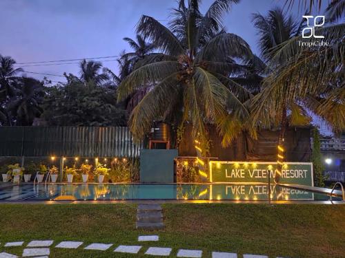 a sign in front of a resort with a palm tree at Lake View Resort by TropiCube in Pamunugama