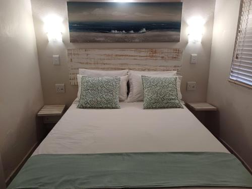 Un dormitorio con una cama grande con dos almohadas. en Banana Beach Club - C10, en Port Shepstone