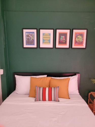 a bedroom with a large white bed with four pictures on the wall at The Open House Cafe and Hostel in Bangkok
