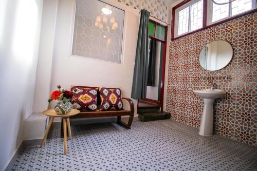 a bathroom with a bench and a sink and a mirror at The Open House Cafe and Hostel in Bangkok