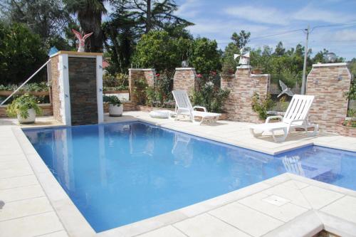a swimming pool with two chairs and a table at O Cantinho da Rosa in Casal Lourenço