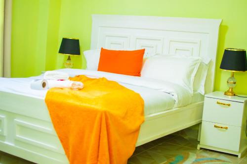 a white bed with an orange blanket on it at Sereni Lounge in Nanyuki