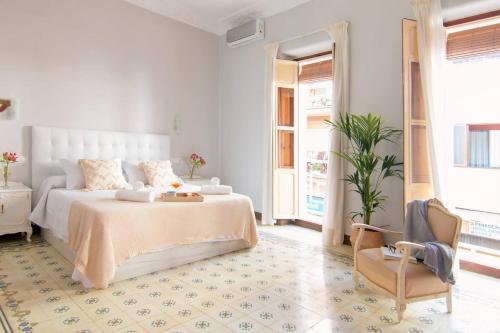 a white bedroom with a bed and a chair at Casa Casanova in Benissa