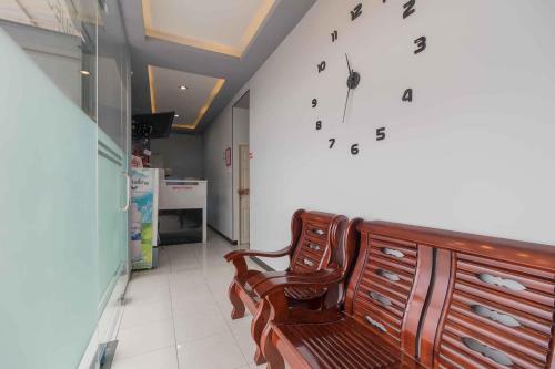 a room with a chair and a clock on the wall at RedDoorz Plus near Millenium ICT Centre Medan 2 in Pulauberayan