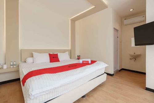 a bedroom with a white bed with a red blanket at RedDoorz Plus near Millenium ICT Centre Medan 2 in Pulauberayan