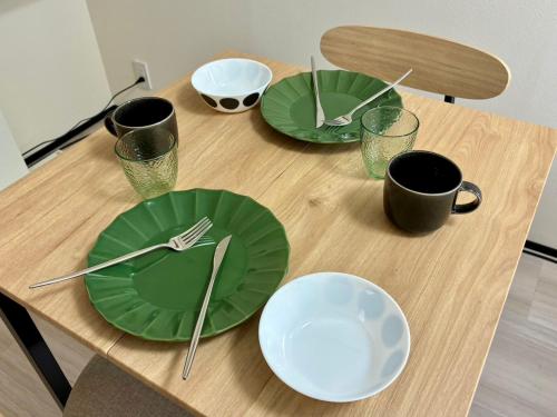 a table with green plates and utensils on it at Corpo SKR by Tranova in Musashino