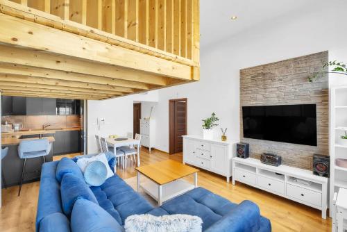 un salon avec un canapé bleu et une télévision dans l'établissement Sky View Family Apartment, à Trnávka