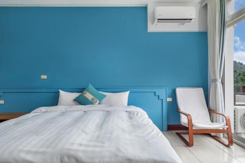 a blue bedroom with a bed and a chair at 米堤園民宿 in Nanzhuang