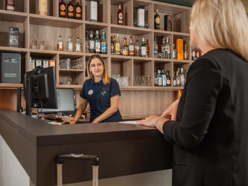 a woman standing at a counter in a bar at ibis Styles Neckarsulm in Neckarsulm