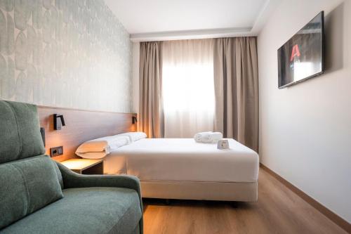 a hotel room with a bed and a couch at Alora Hotel Mérida in Mérida