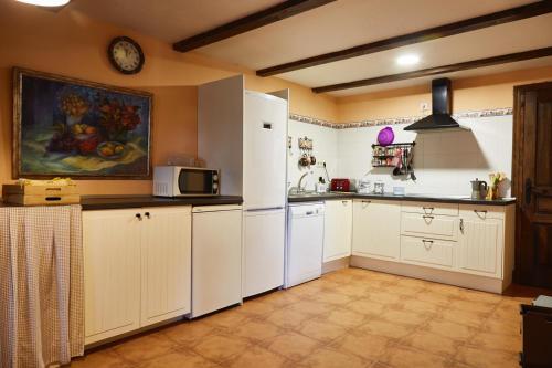 a kitchen with white cabinets and a white refrigerator at Hotel Rural Don Burguillo in El Tiemblo