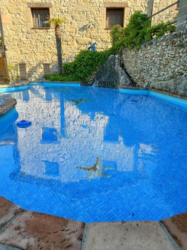 a pool of blue water in front of a building at Cal Fuse in Fonollosa