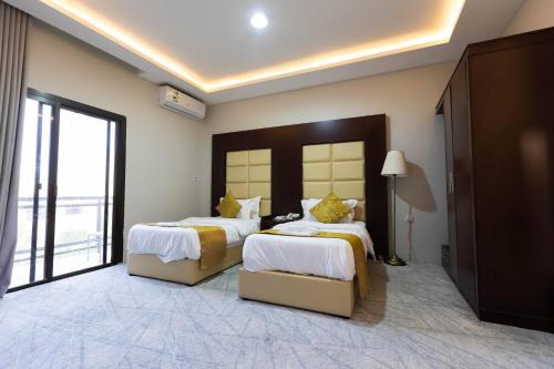 a bedroom with two beds and a large window at فندق السليمانيه والرمال الزرقاء in Riyadh