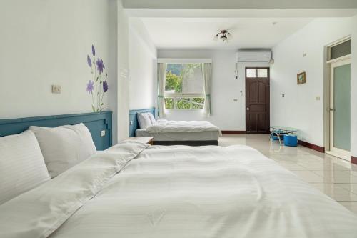 a large white bedroom with two beds in it at 米堤園民宿 in Nanzhuang