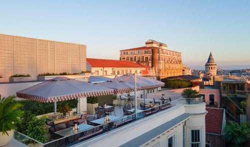 a rooftop bar with tables and umbrellas on a building at Casa Foscolo Hotel, Istanbul, a Member of Design Hotels in Istanbul