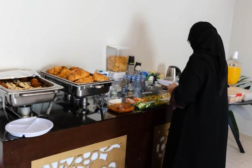a woman standing in a kitchen preparing food at فندق السليمانيه والرمال الزرقاء in Riyadh