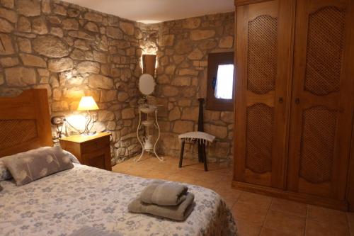 a bedroom with a bed and a stone wall at Cal Fuse in Fonollosa